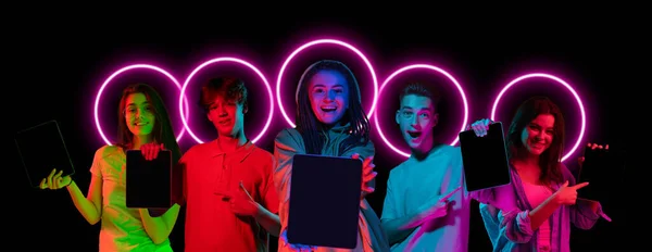 Collage made of multiethnic young people standing together isolated on dark studio background in multicolored neon light with geometric luminescent shape cirlce — Stock Photo, Image