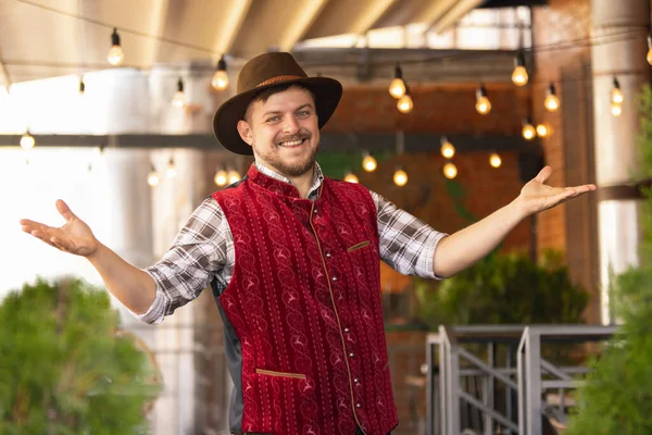 Hombre barbudo caucásico, dueño de restaurante en traje festivo tradicional bávaro saludando a los clientes, visitantes en el bar, cafetería, pub. Oktoberfest —  Fotos de Stock