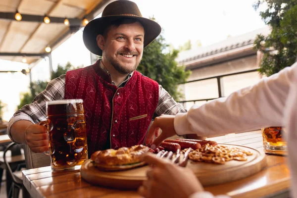 Grupo de amigos se reúnen en el bar, la cafetería y beber cerveza en el festival de la cerveza. Tradiciones, diversión, alegría, amistad, vacaciones. Oktoberfest, octubre, concepto de otoño —  Fotos de Stock