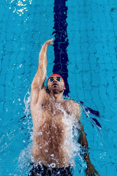 Joven nadador profesional masculino practicando y entrenando en la piscina, en interiores. Estilo de vida saludable, poder, energía, concepto de movimiento deportivo —  Fotos de Stock