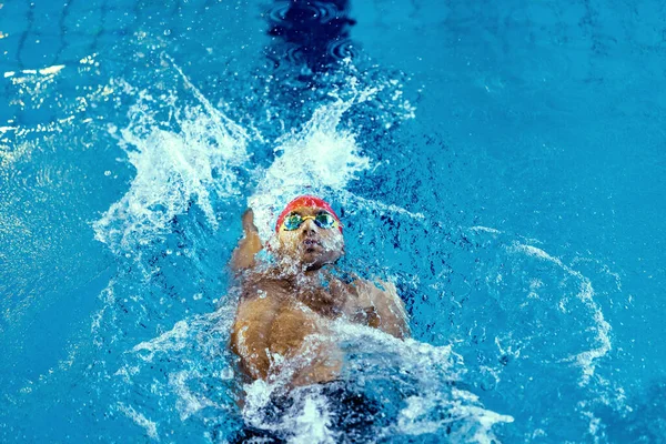 Visão superior do nadador masculino profissional em óculos praticando e treinando na piscina, dentro de casa. Estilo de vida saudável, poder, energia, conceito de movimento desportivo — Fotografia de Stock