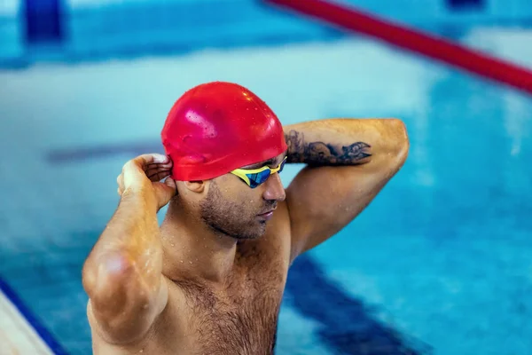 Nahaufnahme Porträt eines jungen Mannes, Schwimmer mit roter Badekappe und Schutzbrille, der sich auf das Training im Schwimmbad vorbereitet. Gesunder Lebensstil, Power, Energie, sportliches Bewegungskonzept — Stockfoto