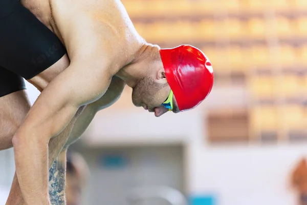 All'inizio. Nuotatore sportivo maschile con cuffia da nuoto rossa e occhialini in movimento e azione durante l'allenamento in piscina, al chiuso. Stile di vita sano, potenza, energia, concetto di movimento sportivo — Foto Stock