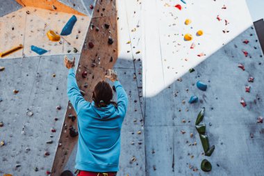Güvenli tırmanış. Genç adam profesyonel kaya tırmanışçısı spor malzemelerini kontrol ediyor güneşli bir günde, açık havada eğitim merkezine tırmanmadan önce..