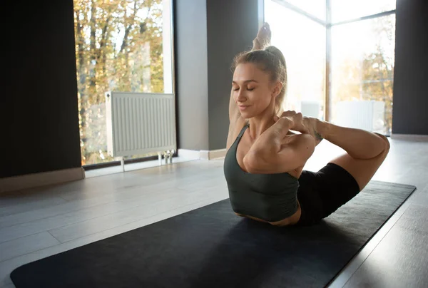 Maestro de yoga. Retrato de una joven mujer deportiva delgada en ropa deportiva haciendo ejercicio en la esterilla deportiva en el centro de meditación de yoga. Concepto de estilo de vida saludable, bienestar, salud mental — Foto de Stock