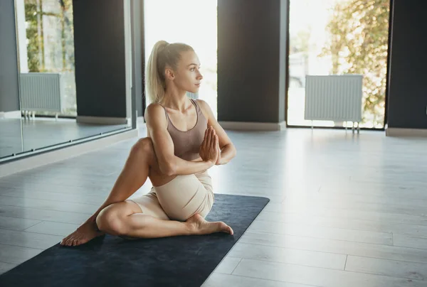 Mestre de ioga. Retrato de jovem mulher esportiva magro em sportswear fazendo complexo de movimentos em tapete esportivo no centro de meditação de ioga. Conceito de estilo de vida saudável — Fotografia de Stock