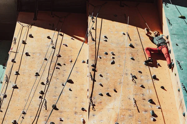 Een blanke man professionele klimmer workouts op klimwand op trainingscentrum in zonnige dag, buiten. Concept van gezonde levensstijl, kracht, kracht, beweging. — Stockfoto