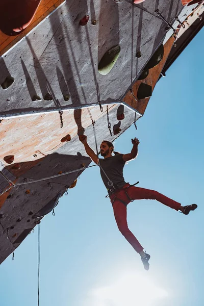 Ein kaukasischer Mann professioneller Bergsteiger beim Training im Trainingszentrum bei sonnigem Wetter im Freien. Konzept des gesunden Lebensstils, Tourismus, Natur, Bewegung. — Stockfoto