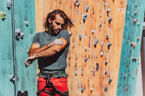 Portrait of Caucasian man professional rock climber standing at front of climbing wall at training center in sunny day, outdoors. Concept of healthy lifestyle, sport, motion. — Stock Photo, Image