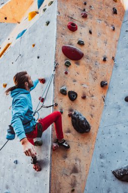 Genç adam profesyonel kaya tırmanışçısı güneşli bir günde, açık havada antrenman yapıyor. Sağlıklı yaşam tarzı kavramı, turizm, doğa, hareket.