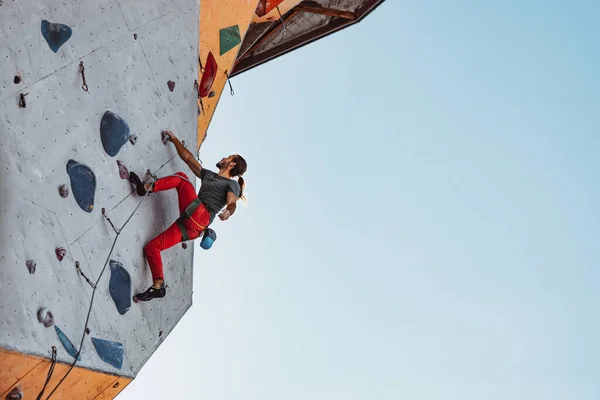 Junger Mann professioneller Bergsteiger beim Training im Trainingszentrum bei sonnigem Wetter im Freien. Konzept des gesunden Lebensstils, Tourismus, Natur, Bewegung. — Stockfoto