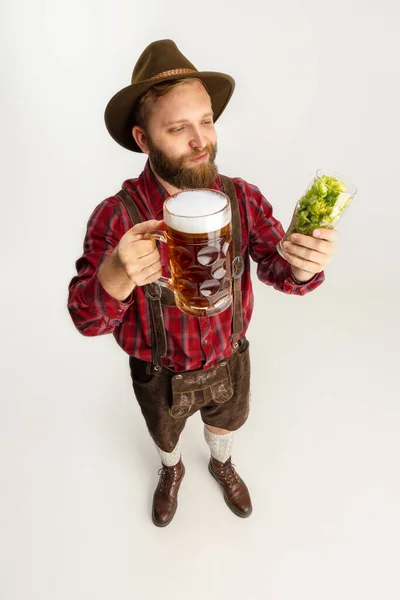 Fiatal szakállas férfi, pincér hagyományos bajor jelmezben, kezében söröspoharakkal, tele vad forrósággal és sörrel. Ünnep, oktoberfest, fesztivál koncepció. — Stock Fotó