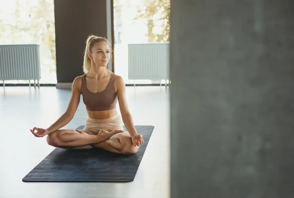 Yoga dersi. Spor kıyafetli genç kızın portresi yoga meditasyon merkezinde spor minderi üzerinde egzersiz yapıyor. Sağlıklı yaşam tarzı, refah, akıl sağlığı kavramı — Stok fotoğraf