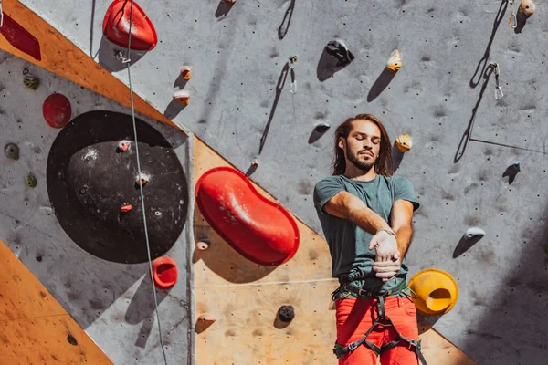 Portrait de l'homme caucasien grimpeur professionnel se réchauffe devant le mur d'escalade au centre d'entraînement par temps ensoleillé, à l'extérieur. Concept de mode de vie sain, sport, mouvement. — Photo