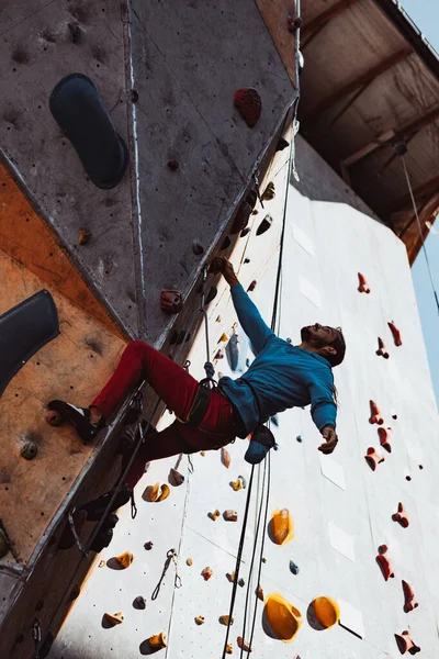 Entraînement quotidien. Jeune homme alpiniste professionnel pratiquant au centre d'entraînement par temps ensoleillé, en plein air. Concept de mode de vie sain, activité physique — Photo