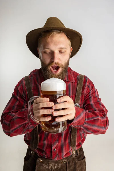 Ritratto a mezza lunghezza di uomo barbuto in cappello e costume tradizionale bavarese con enorme tazza, vetro di birra schiumosa leggera isolato su sfondo bianco. Volantino — Foto Stock
