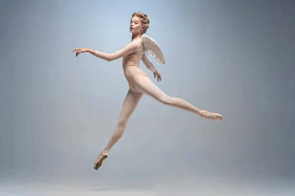 Młoda i pełna wdzięku tancerka baletowa, balerina tańcząca na białym szarym tle studia. Sztuka, ruch, działanie, elastyczność, koncepcja inspiracji. — Zdjęcie stockowe