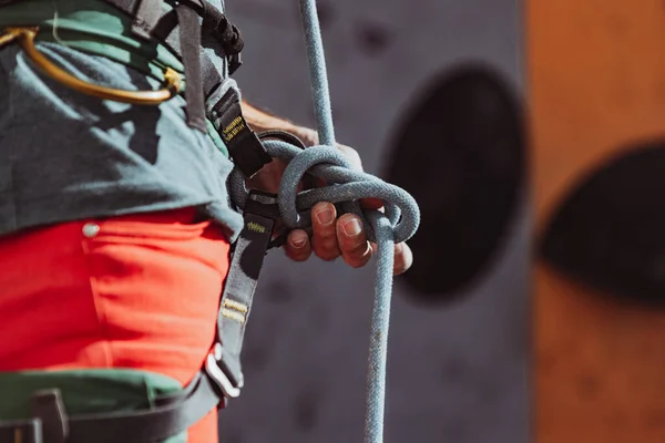 Säkerhetsklättring. Ung man professionell bergsklättrare kontrollera sportutrustning innan klättring på träningscentret i solig dag, utomhus. — Stockfoto