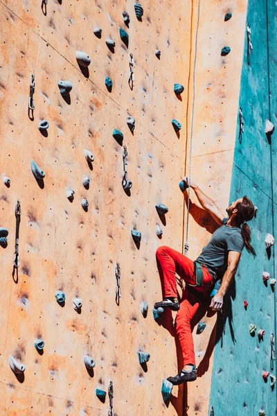 Un uomo caucasico professionista arrampicatore allenamenti sulla parete di arrampicata al centro di formazione nella giornata di sole, all'aperto. Concetto di stile di vita sano, potenza, forza, movimento. — Foto Stock