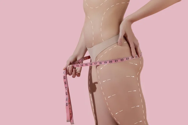 Detailní záběr krásné ženské tělo, hýždě s zvedání šípy izolované na růžovém pozadí. Koláž. Odolná pokožka, fitness tělo, procedury proti celulitidě. — Stock fotografie