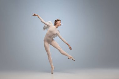 Genç ve zarif balerin, gri stüdyo arka planında kanatları izole edilmiş melek görüntüsü ile dans eden balerin. Sanat, hareket, eylem, esneklik, ilham kavramı.