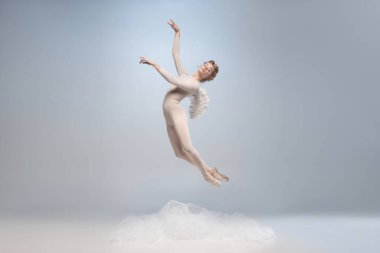Genç ve zarif balerin, gri stüdyo arka planında kanatları izole edilmiş melek görüntüsü ile dans eden balerin. Sanat, hareket, eylem, esneklik, ilham kavramı.