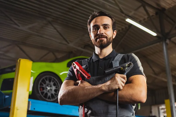 Araba servis istasyonunda. Genç bir adam, kapalı mekanda araba servisinde çalışan, kot pantolonlu bir erkek tamirci. Çalışma kavramı, meslek, iş, kariyer, iş