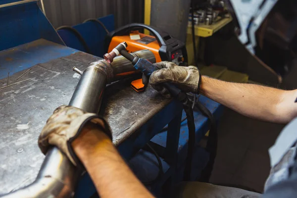 Cropped image of male auto mechanic in dungarees with work tools working at car service station, indoors. Concept of labor, occupation, business, caree, job — Stock Photo, Image