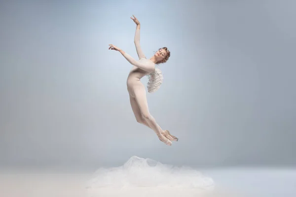 Młoda i pełna wdzięku tancerka baletowa, balerina tańcząca w obrazie anioła ze skrzydłami odizolowanymi na szarym tle pracowni. Sztuka, ruch, działanie, elastyczność, koncepcja inspiracji. — Zdjęcie stockowe