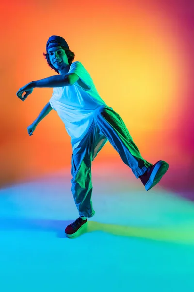 Κοντινό πλάνο πορτρέτο του νεαρού άνδρα, hip-hop χορευτή με κομψά ρούχα σε δράση απομονωμένο σε πολύχρωμο φόντο στην αίθουσα χορού στο νέον φως. — Φωτογραφία Αρχείου