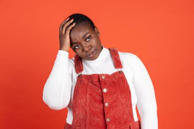 Kırmızı stüdyo arka planında izole edilmiş Afrikalı üzgün kadının parlak portresi. İnsan duyguları kavramı, yüz ifadesi, doğal güzellik, vücut pozitifliği
