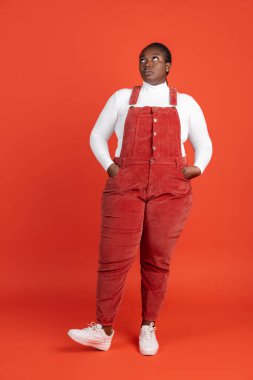 Kırmızı stüdyo arka planında izole edilmiş Afrikalı mutlu kadının parlak portresi. İnsan duyguları kavramı, yüz ifadesi, doğal güzellik, vücut pozitifliği