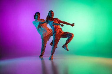 Genç hip-hop dansçıları, şık duygusal kız ve erkek, günlük spor kıyafetleri içinde hareket halindeler. Neon ışıklı dans salonunda çok renkli arka planda..