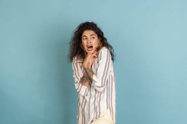 Güzel bir kızın yarım boy fotoğrafı, elinde açık mavi stüdyo arka planında izole edilmiş dövmesi olan bir model. Duygular, duygular kavramı