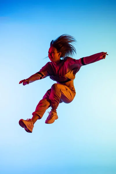 One young sportive girl dancing hip-hop in stylish clothes on colorful background at dance hall in neon light. Youth culture, movement, style and fashion, action. — Stock Photo, Image