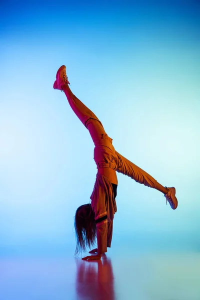 Jeune fille sportive dansant break dance seule isolée sur fond coloré à la salle de danse au néon. Culture, mouvement, style et mode des jeunes, action. — Photo