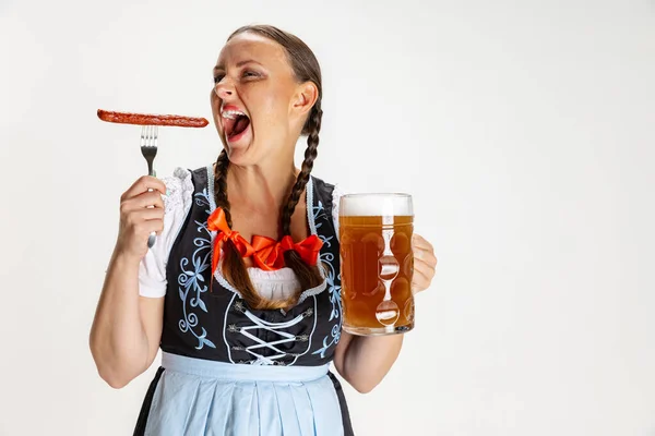 Jonge mooie vrouw, serveerster in traditionele Oostenrijkse of Beierse kostuum met enorme bierglas en eten worst geïsoleerd over witte achtergrond. — Stockfoto