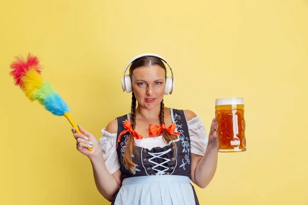 Retrato cómico de la hermosa mujer Oktoberfest, camarera con un dirndl tradicional bávaro o alemán aislado en el fondo del estudio amarillo. — Foto de Stock