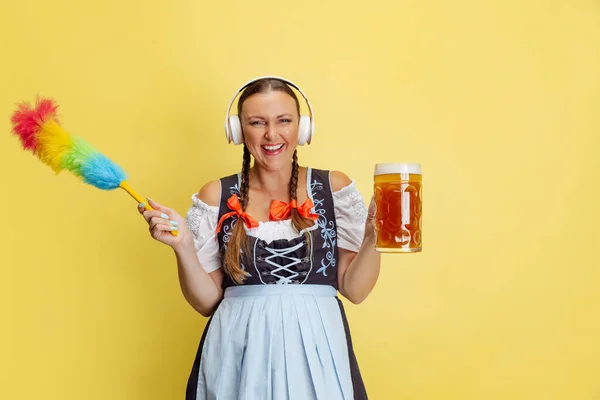 Retrato cómico de la hermosa mujer Oktoberfest, camarera con un dirndl tradicional bávaro o alemán aislado en el fondo del estudio amarillo. — Foto de Stock