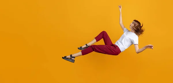 Studio záběr mladé roztomilé dívky izolované padající izolované na žluté pozadí barevného studia. Pojem lidské emoce, výraz obličeje — Stock fotografie