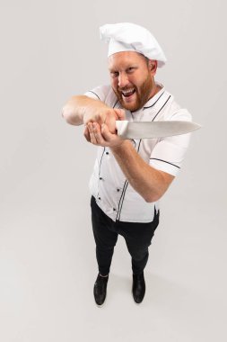 Yüksek açılı bir manzarası vardı. Sakallı bir adam, aşçı, beyaz üniformalı bir erkek şef beyaz arka planda izole edilmiş eğleniyordu. İş, meslek, mizah anlayışı.