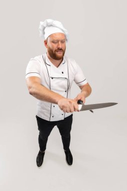 Yüksek açılı bir manzarası vardı. Sakallı bir adam, aşçı, beyaz üniformalı bir erkek şef beyaz arka planda izole edilmiş eğleniyordu. İş, meslek, mizah anlayışı.