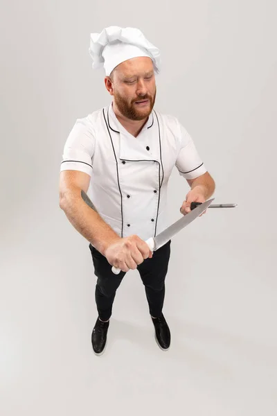 Vista de alto ângulo do homem barbudo hadsome, cozinheiro, chef masculino em uniforme branco se divertindo isolado no fundo branco. Conceito de trabalho, ocupação, humor. — Fotografia de Stock