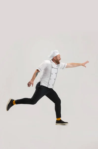 Portrait of cook, chef man in uniform running to kitchen isolated on white background. Concept of job, occupation, humor. — Stock Photo, Image