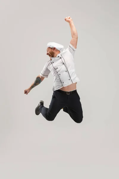 One Caucasian bearded man, chef in uniform jumping high isolated on white background. Concept of job, occupation, humor. — Stock Photo, Image