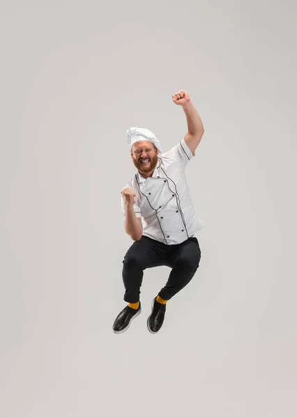 Jeden běloch s vousy, kuchař v uniformě, skákal vysoko izolovaný na bílém pozadí. Pojetí práce, povolání, humor. — Stock fotografie
