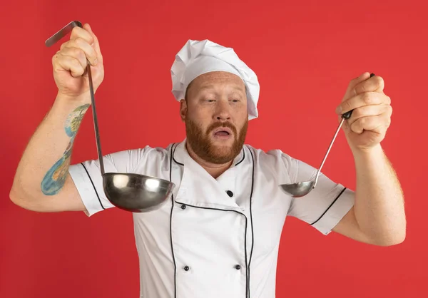 붉은 스튜디오 배경에는 수염을 기른 남자, 요리사, 흰 제복을 입은 남자 요리사의 생생 한 초상화가 있다. 직업, 직업, 유머에 대한 개념. — 스톡 사진