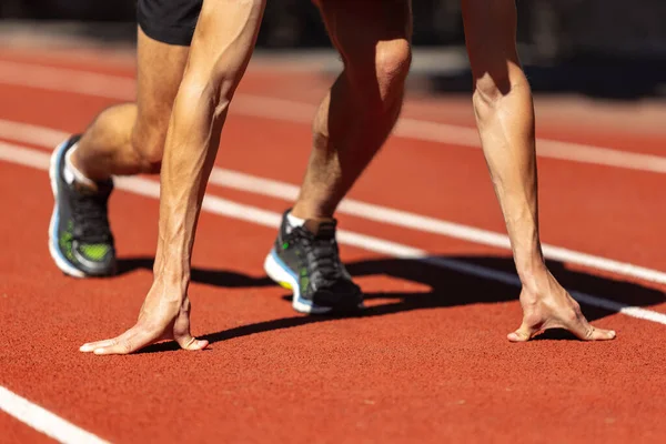 Un joven deportista, atleta masculino, corredor practicando solo antes de la carrera en el estadio público, pista deportiva o pista de atletismo, al aire libre. Juegos de deporte profesional. — Foto de Stock