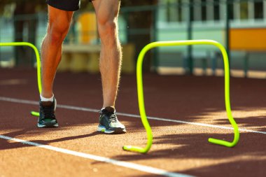 Erkek sporcunun kırpılmış görüntüsü, stadyumdaki koşucu eğitimi, spor sahası ya da açık hava koşusu. Yaz sporları oyunları. Erkek bacakları