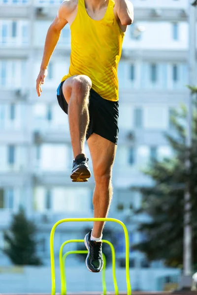 Junger kaukasischer Sportler, männlicher Athlet, Läufer, der im öffentlichen Stadion, auf dem Sportplatz oder auf der Laufbahn im Freien hoch springt. Sommersportspiele. — Stockfoto